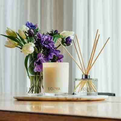 ECOYA candle and ECOYA diffuser on a tray. Purple flowers in background
