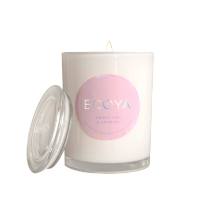 ECOYA metro candle in sweet pea fragrance. Glass candle jar with lid off and pink label on front